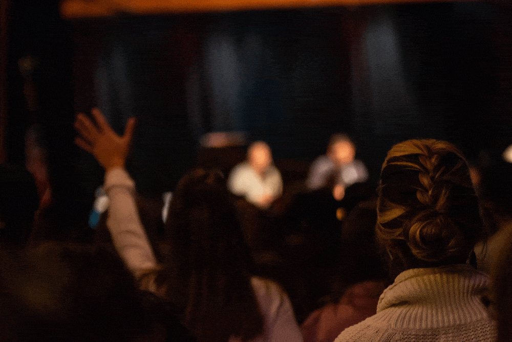 photo of back of woman's head with two worship leaders blurred in the background